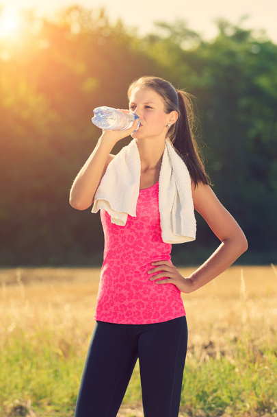 Atractiva hembra tomando un descanso después de trotar, sosteniendo la botella de agua
 - Foto, Imagen