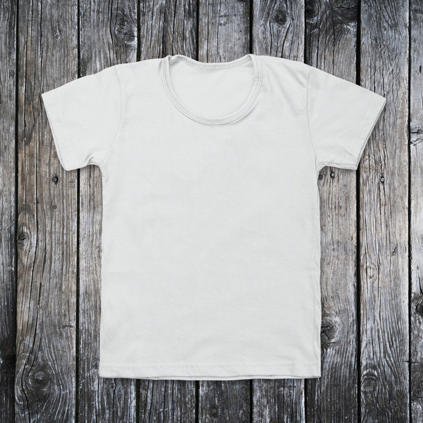 White blank t-shirt on dark wood desk - Foto, imagen