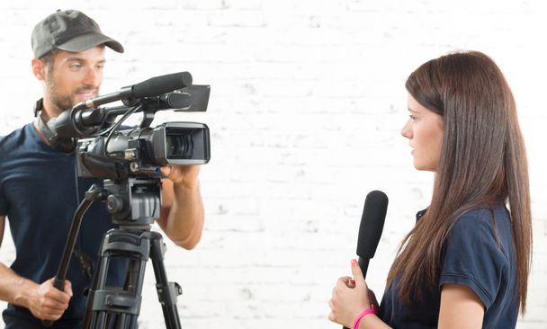 uma jovem jornalista com um microfone e um operador de câmara
 - Foto, Imagem