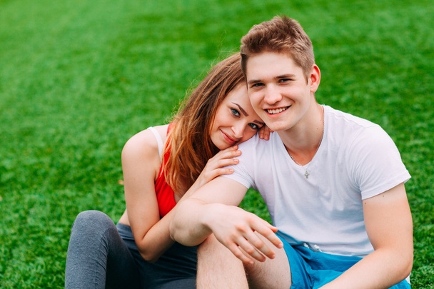 Młoda para lekkoatletycznego siedząc na trawie - Zdjęcie, obraz