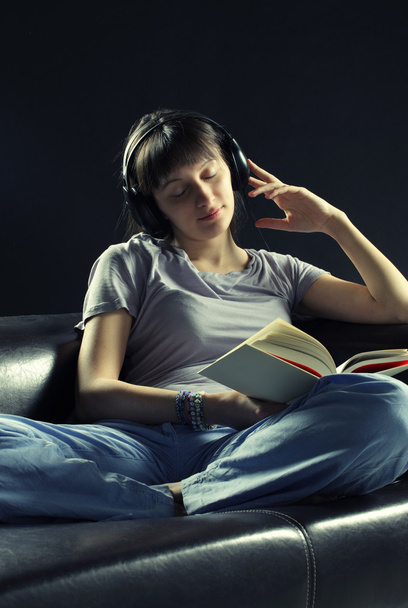 Relaxed young woman listening music and reading a book - Фото, изображение