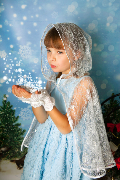 roztomilá holčička v modré šaty s krajkou mys fouká v snowf - Fotografie, Obrázek