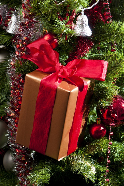 Presente com fita vermelha na árvore de Natal
 - Foto, Imagem