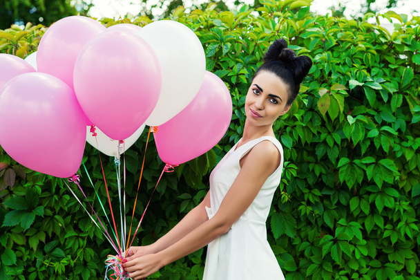 mooie vrouw met ballonnen op een achtergrond van groene Hagen - Foto, afbeelding