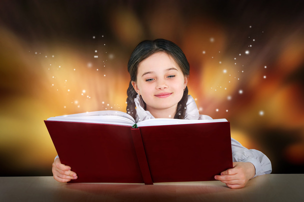Niña adolescente lee un libro mágico tutorial de hadas sonriendo
 - Foto, imagen
