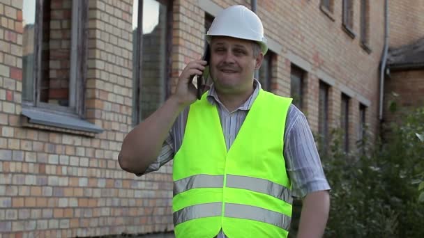 Building inspector talking on smartphone - Кадры, видео