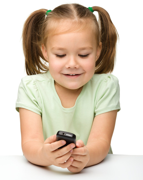 Cute little girl is playing with cell phone - Fotó, kép