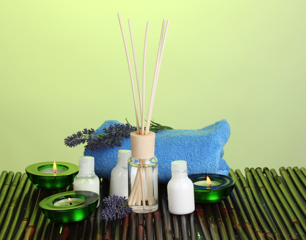 Osvěžovač vzduchu, lahve, ručník a svíčky na bambusové rohoži na zeleném pozadí - Fotografie, Obrázek