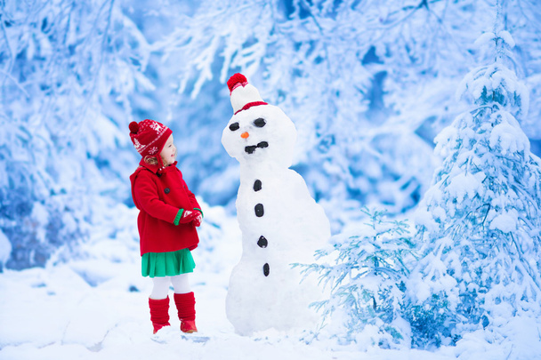 Malá holčička budování sněhu muž v zimě - Fotografie, Obrázek