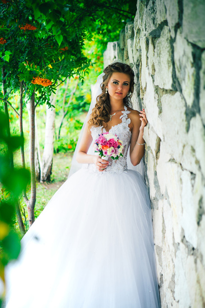 Beautiful young bride standing on a stone wall background - Photo, Image