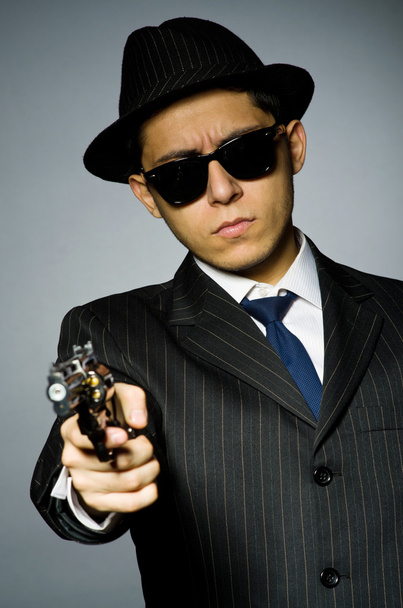 homme en costume élégant tenant une arme de poing
 - Photo, image