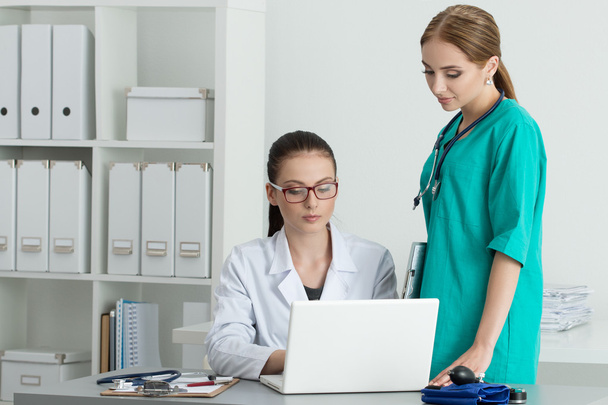 Дві красиві лікарі жіночої медицини дивляться на монітор ноутбука
 - Фото, зображення