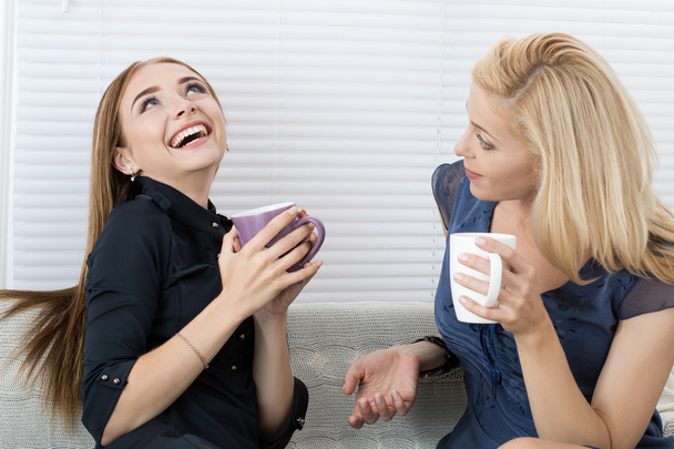 Kaksi naispuolista ystävää juttelee ja nauraa yhdessä
 - Valokuva, kuva