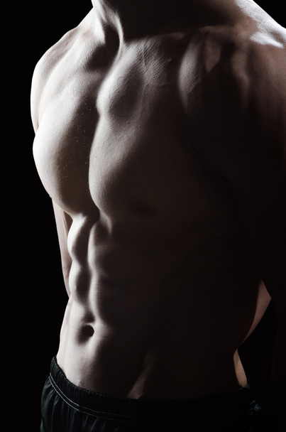 Uomo muscolare in posa in studio scuro - Foto, immagini