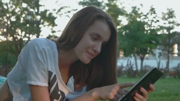 Pretty teen girl is working in internet outdoors - Materiał filmowy, wideo