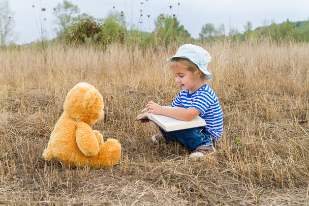 Leuk meisje lezen boek Teddy bear - Foto, afbeelding