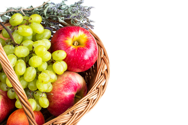 White background  with Ripe red Apples, dry marjoram herbs and green grapes in the basket - Photo, Image