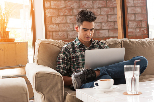 Empresário usando laptop no sofá no café com uma xícara de co
 - Foto, Imagem