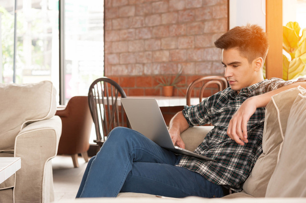 Бізнесмен використовує ноутбук на дивані в кав'ярні
 - Фото, зображення
