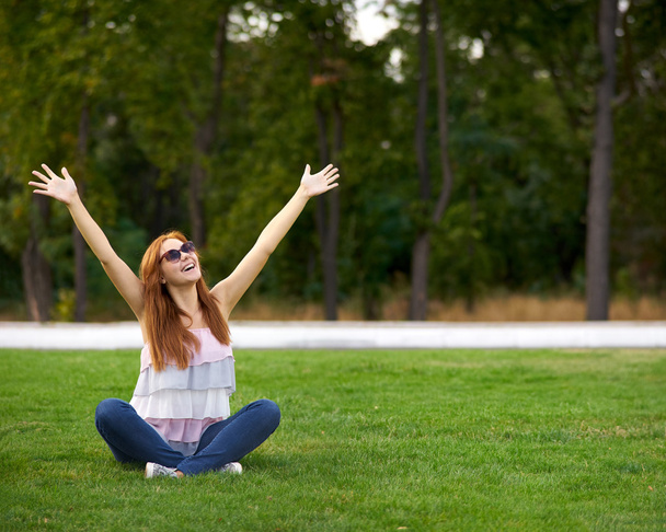 sorrindo mulher sentada no gramado verde
 - Foto, Imagem