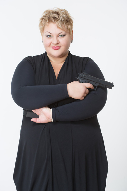 fat woman with a gun. in a black dress - Fotoğraf, Görsel