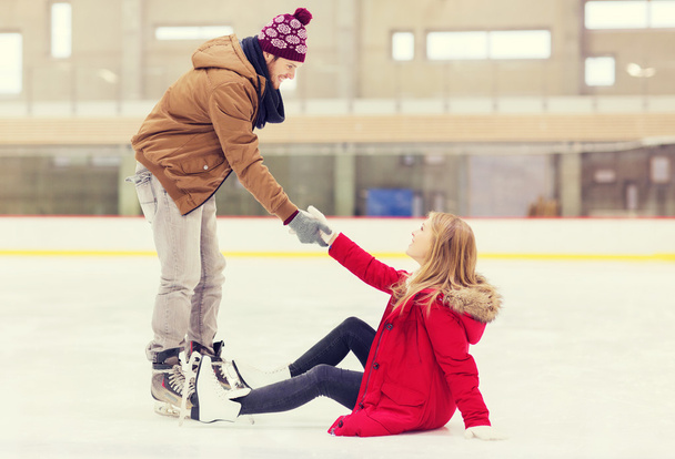man helping women to rise up on skating rink - Foto, Imagem