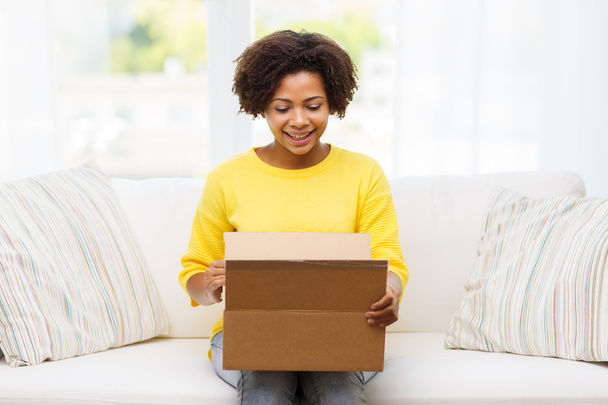 happy african young woman with parcel box at home - Фото, изображение