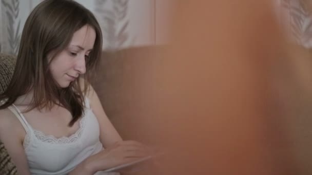 νεαρή γυναίκα διαβάζει ένα βιβλίο στον καναπέ - Πλάνα, βίντεο