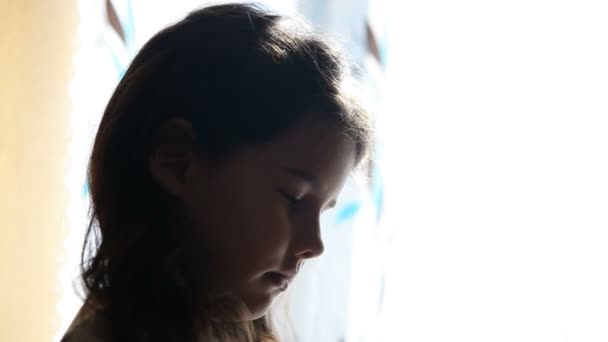 Dívek se modlí stál u okna siluetu Video dětství náboženství - Záběry, video