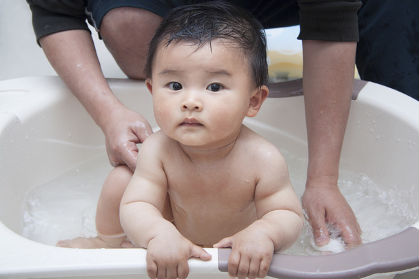 Pai chinês lavando bebê na banheira
 - Foto, Imagem