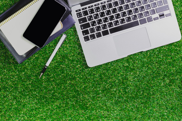 blank notebook, phone, laptop and headphone on green grass - Foto, immagini