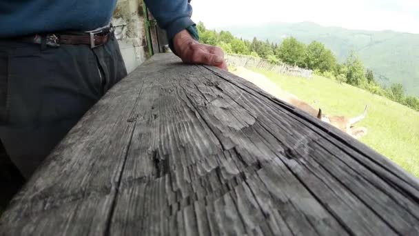 a mão do velho repousa sobre o largo corrimão de madeira de perto
 - Filmagem, Vídeo