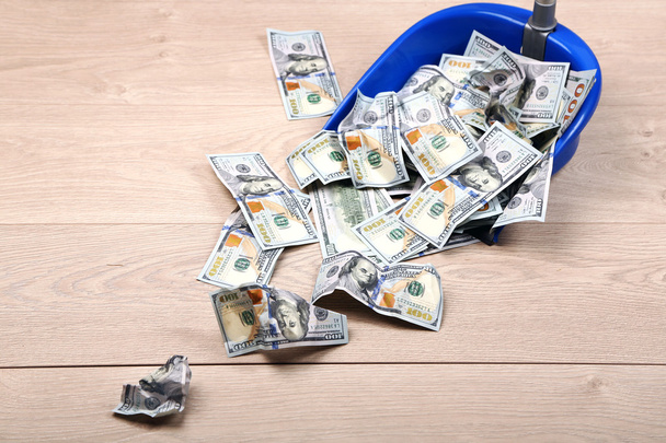 Dollars in garbage scoop on wooden floor background - Foto, Imagem