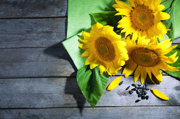 Beautiful bright sunflowers with seeds on wooden table close up - 写真・画像