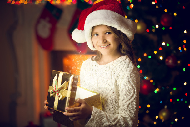 portrait of smiling girl in Santa cap posing with glowing gift b - Foto, afbeelding