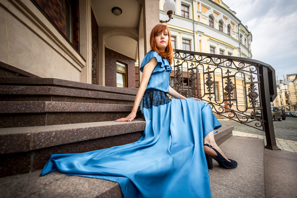 mulher ruiva em vestido azul posando em escadas no edifício velho
 - Foto, Imagem
