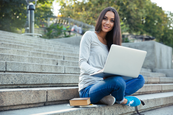 Female student using laptop computer outdoors - 写真・画像