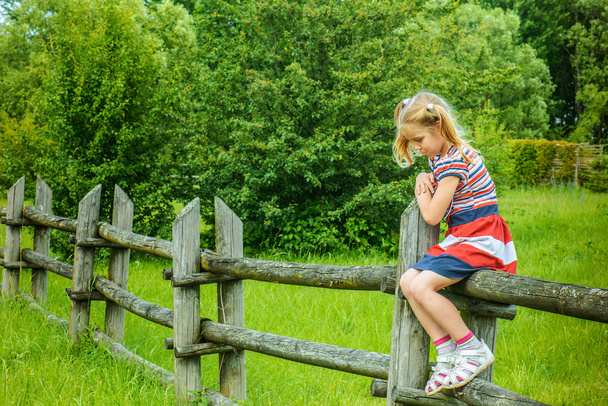 szomorú lány ül a fából készült kerítés - Fotó, kép