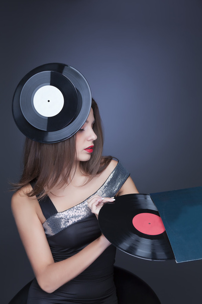 Girl with a vinyl record on a dark background - Foto, afbeelding