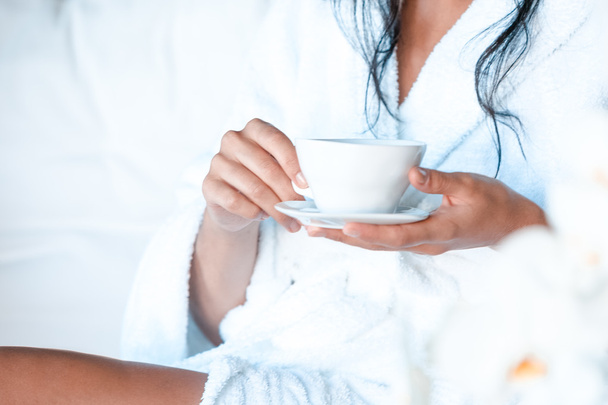 Young woman in a bathrobe with a cup of tea - Foto, afbeelding