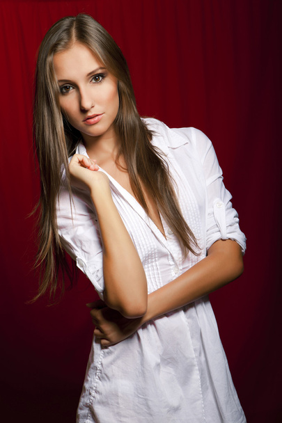 Beautiful brunette girl in white before red - Фото, изображение