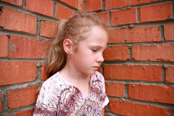 Sad child with a brick wall - Foto, afbeelding