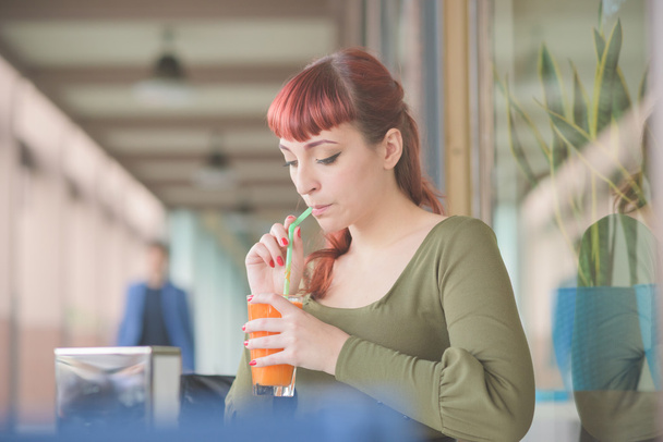 junge hübsche rothaarige Frau trinkt Saft - Foto, Bild