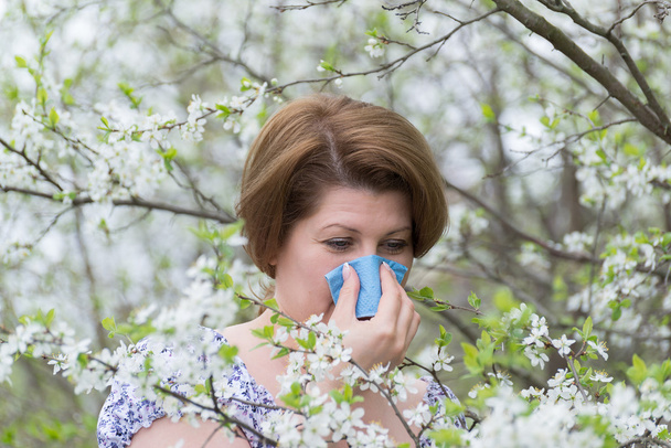 Woman with allergic rhinitis in  spring garden - Foto, afbeelding