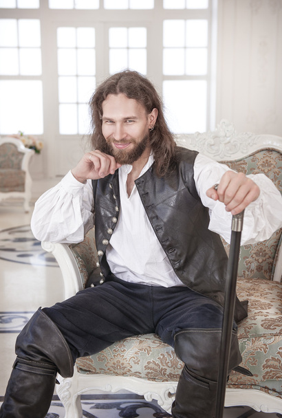 Przystojny mężczyzna w średniowiecznych ubraniach siedząc w fotelu - Zdjęcie, obraz