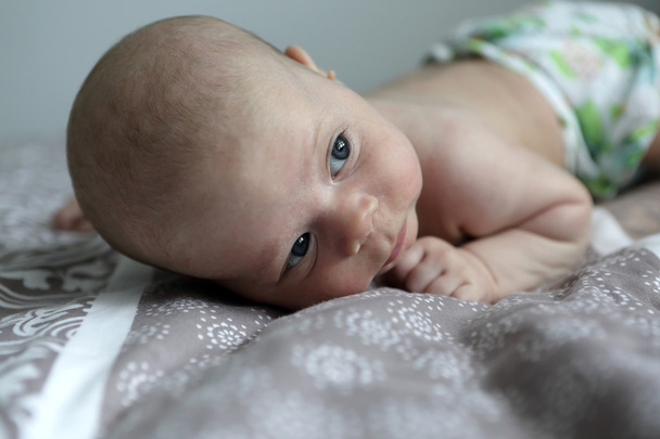 Pensive baby on a bed - 写真・画像