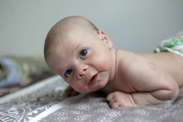 Pensive newborn baby boy on a bed - Photo, Image