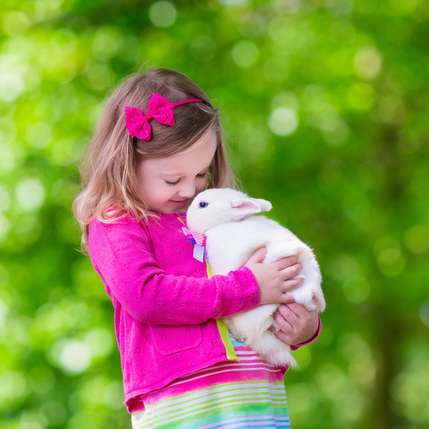 Маленькая девочка играет с кроликом
 - Фото, изображение