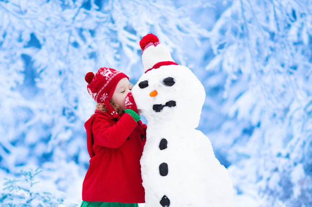 Pieni tyttö rakentaa lumiukko
 - Valokuva, kuva