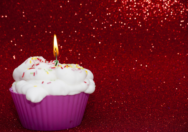Cupcake avec une bougie allumée sur fond rouge vif
 - Photo, image